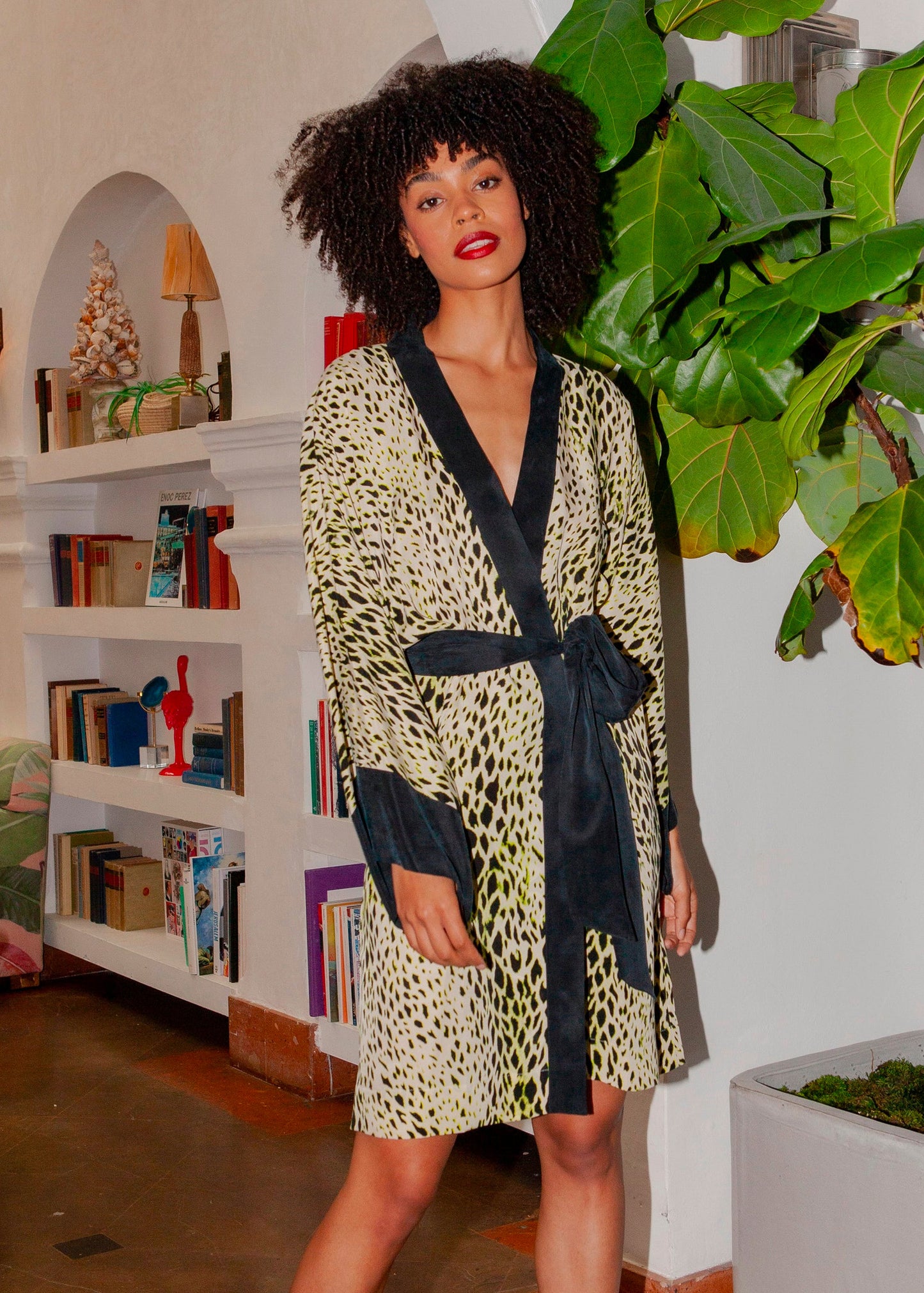 Woman wearing a light animal-print wrap robe with black trim and a tie belt