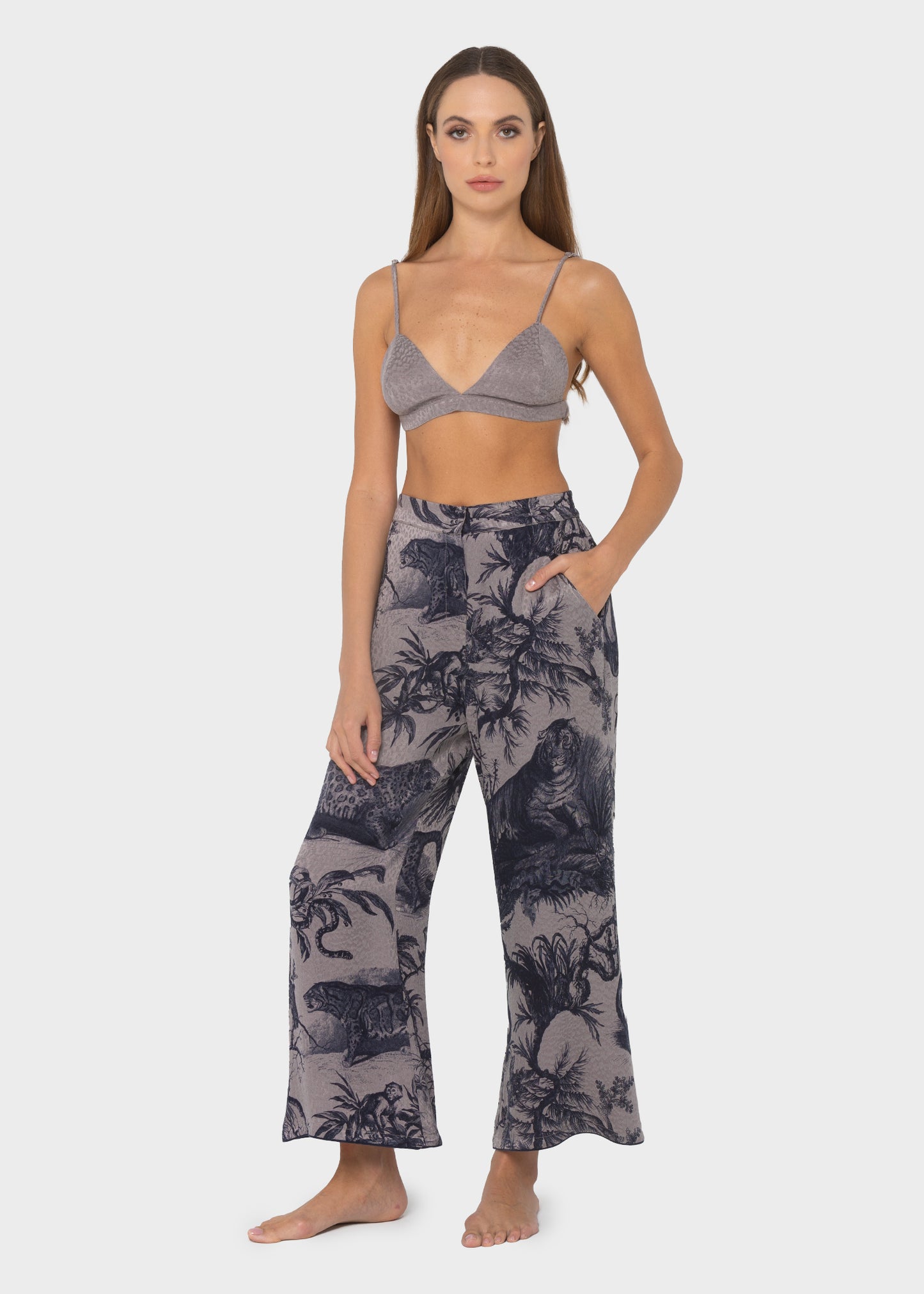 Woman wearing a gray triangle bralette with thin straps and matching gray textured skirt