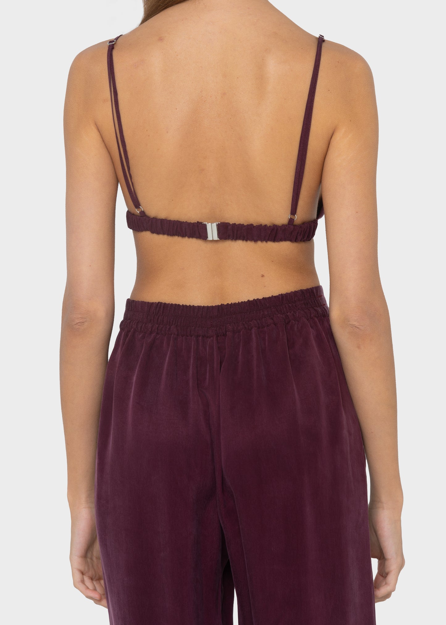 Women wearing a burgundy vegan silk bralette with matching high-waist pants.
