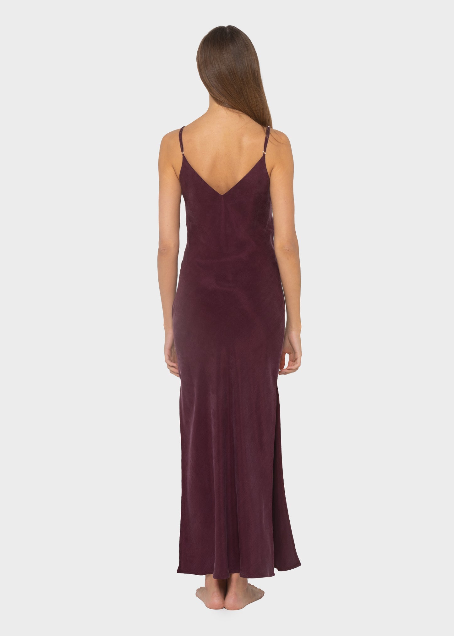 Women wearing burgundy vegan silk slip dress with a side slit, strappy heels.