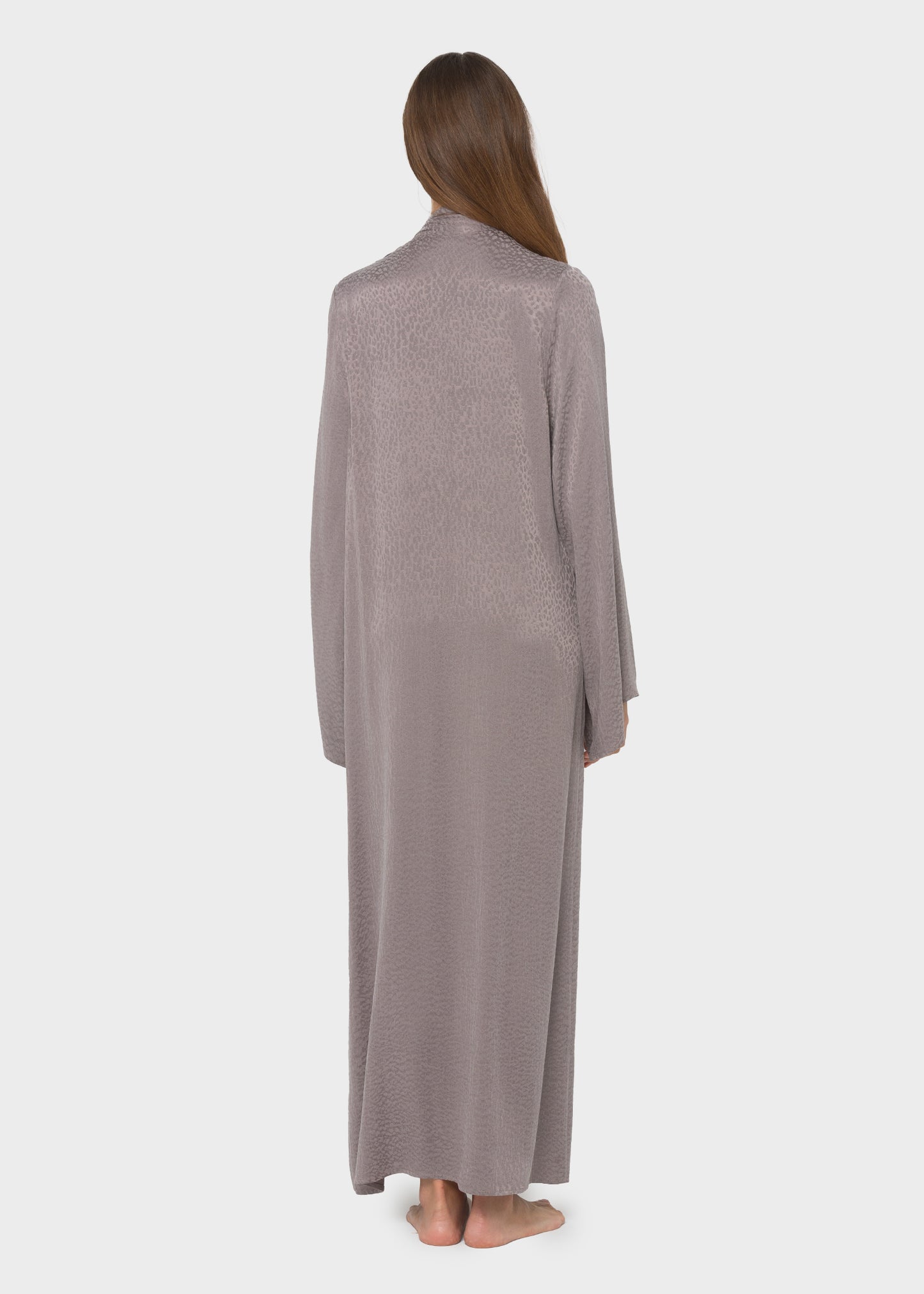 Woman wearing a gray textured maxi dress with a pussy bow tie neckline and long sleeves