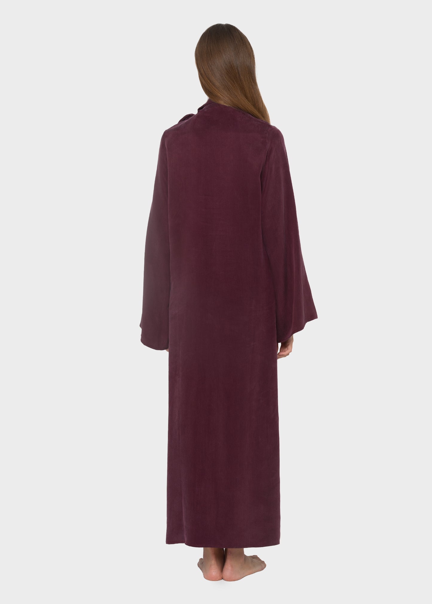 Woman wearing a burgundy maxi dress with a pussy bow tie neckline and long sleeves