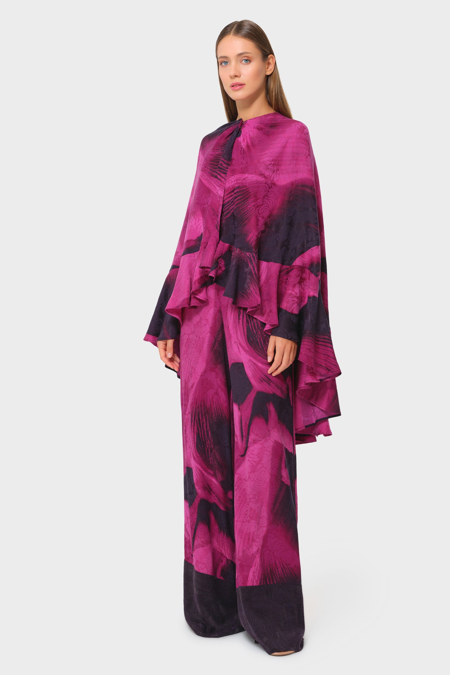 Model in pink and black printed cape-style top with matching long skirt