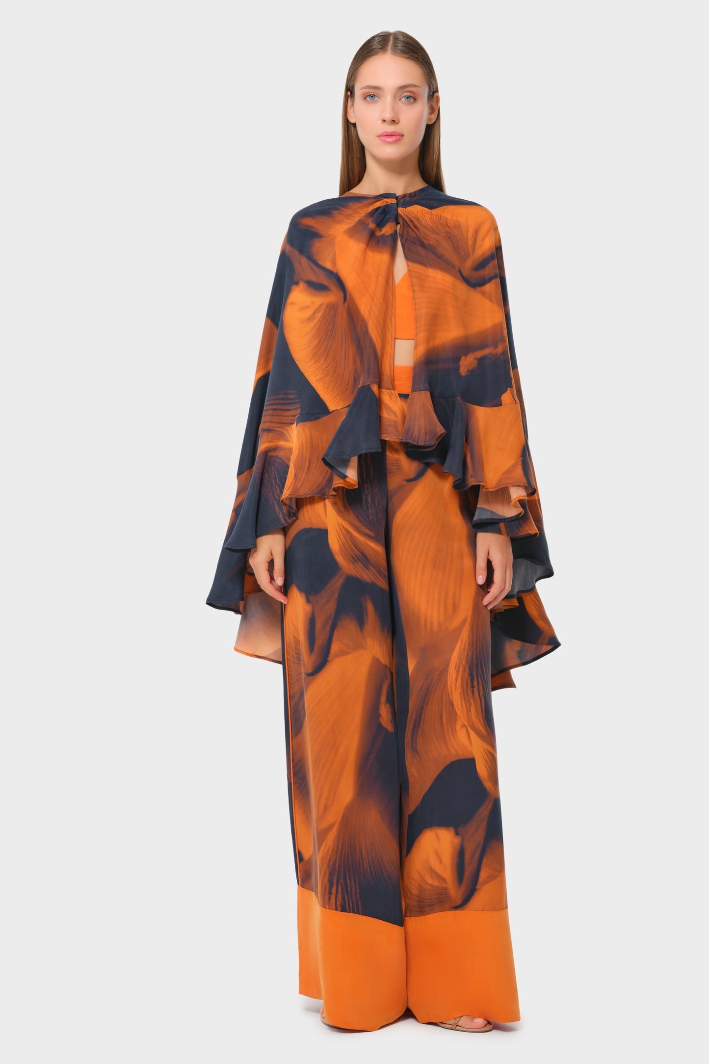 Model in navy and orange printed cape-style top with matching long skirt