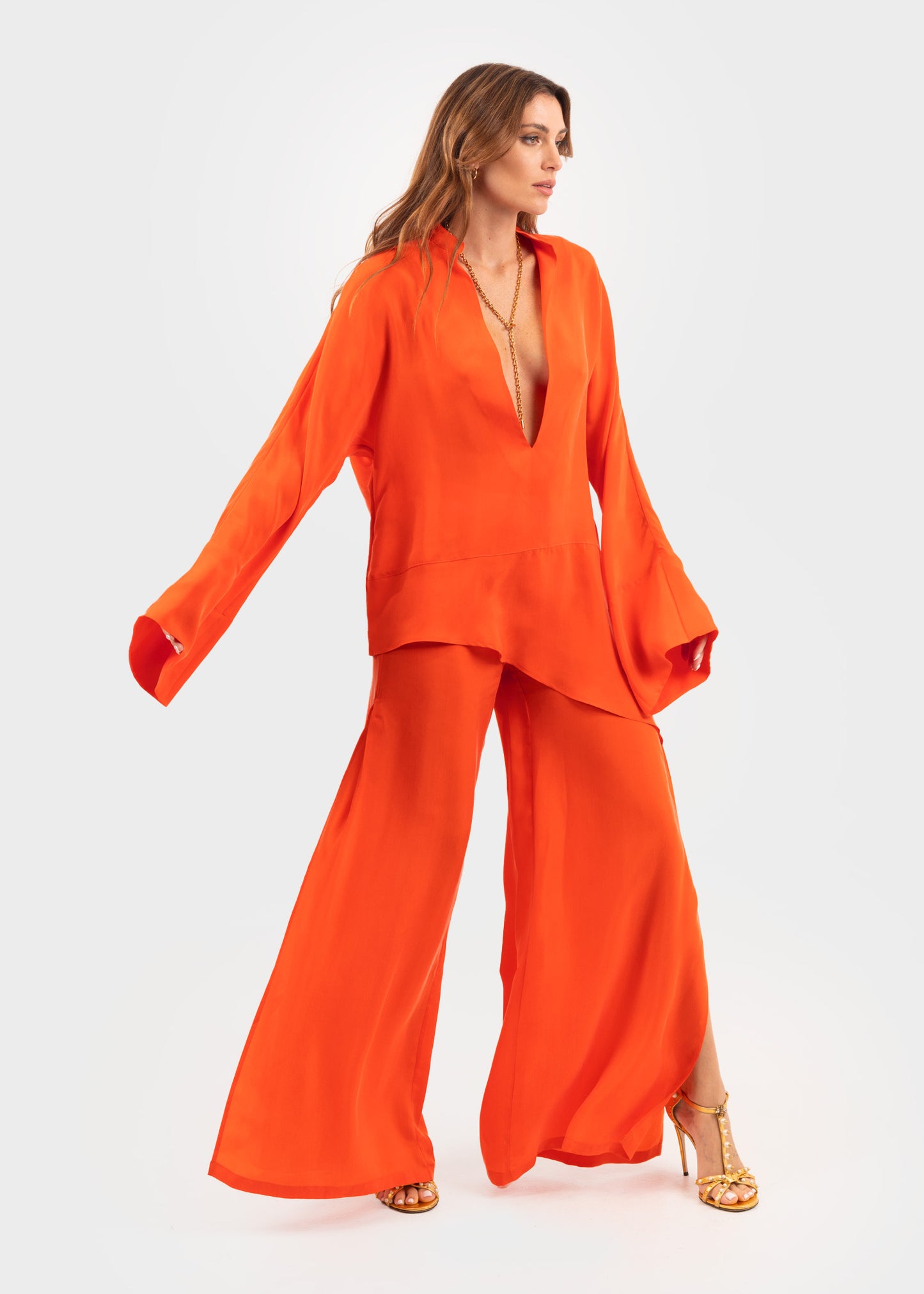 Women wearing a bright orange vegan silk tunic and matching wide-leg pants.
