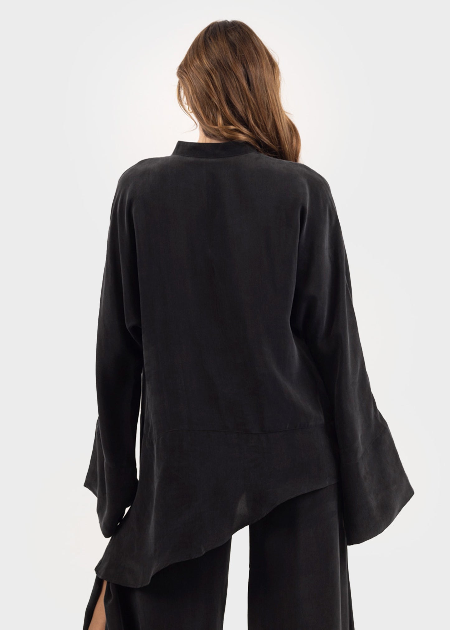 Woman wearing a black oversized tunic top with a deep V-neckline and flutter sleeves