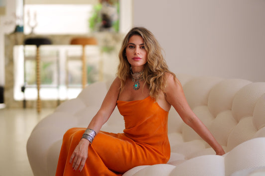 Dalia El Ali seated on a white sofa wearing an orange dress showcasing effortless elegance and style