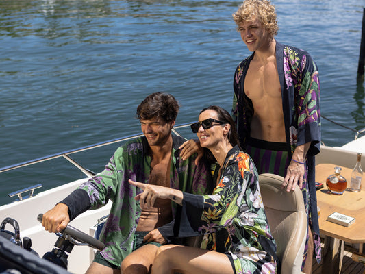 Three people wearing vibrant vegan silk kimonos relax on a boat, enjoying the sun and water as they embody niLuu’s effortless, elegant approach to travel.