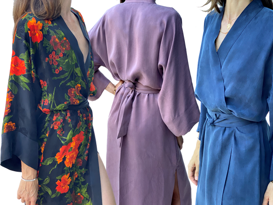 Three women showcase niLuu vegan silk robes in vibrant floral, soft mauve, and deep blue hues, highlighting their fluid drape and elegant kimono-inspired design.