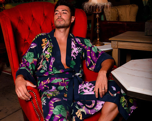 A man with tan skin sitting on a red sofa chair wearing a men’s kimono from niLuu.