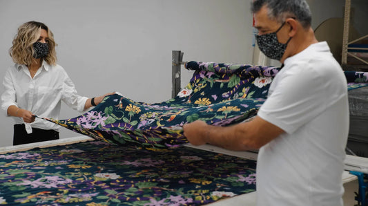 A woman and a man, both professionals dressed in white, working on vegan silk cloth at niLuu.