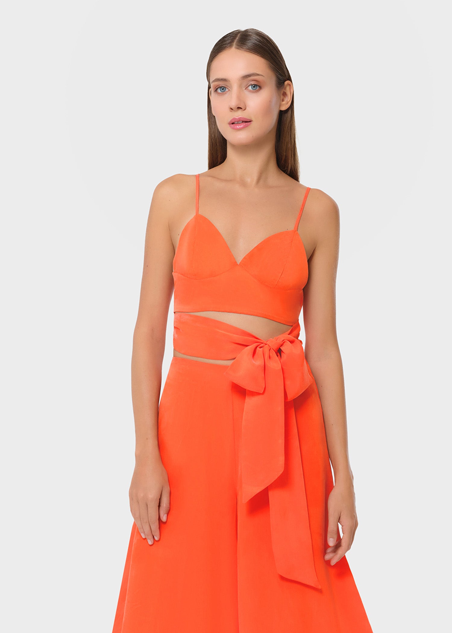 Woman wearing bright orange vegan silk bralette and bow tie maxi skirt, front view