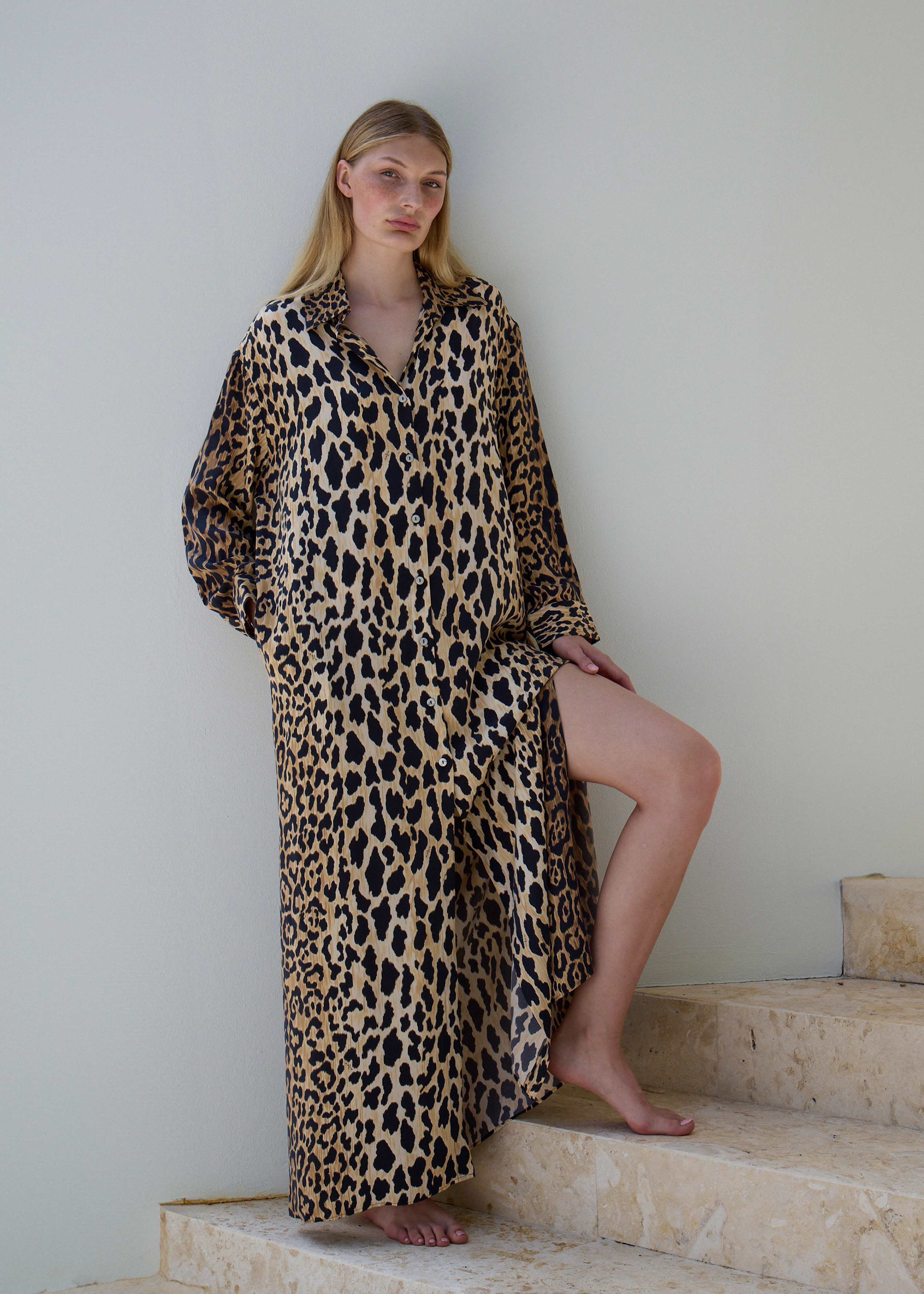 Model wearing leo calypso maxi dress on stairs against white wall