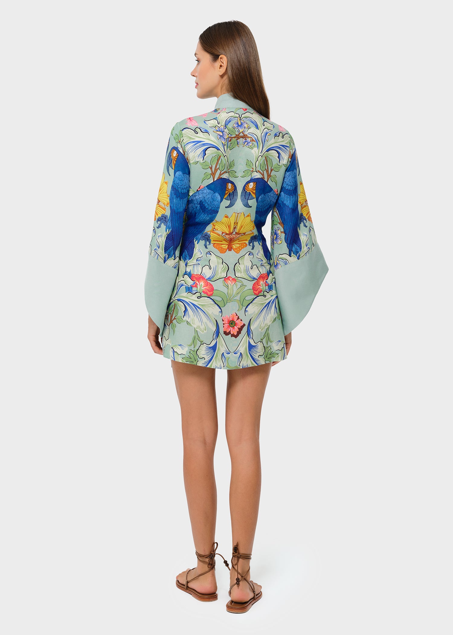 Back view of a light green parrot print kimono mini robe with wide sleeves.