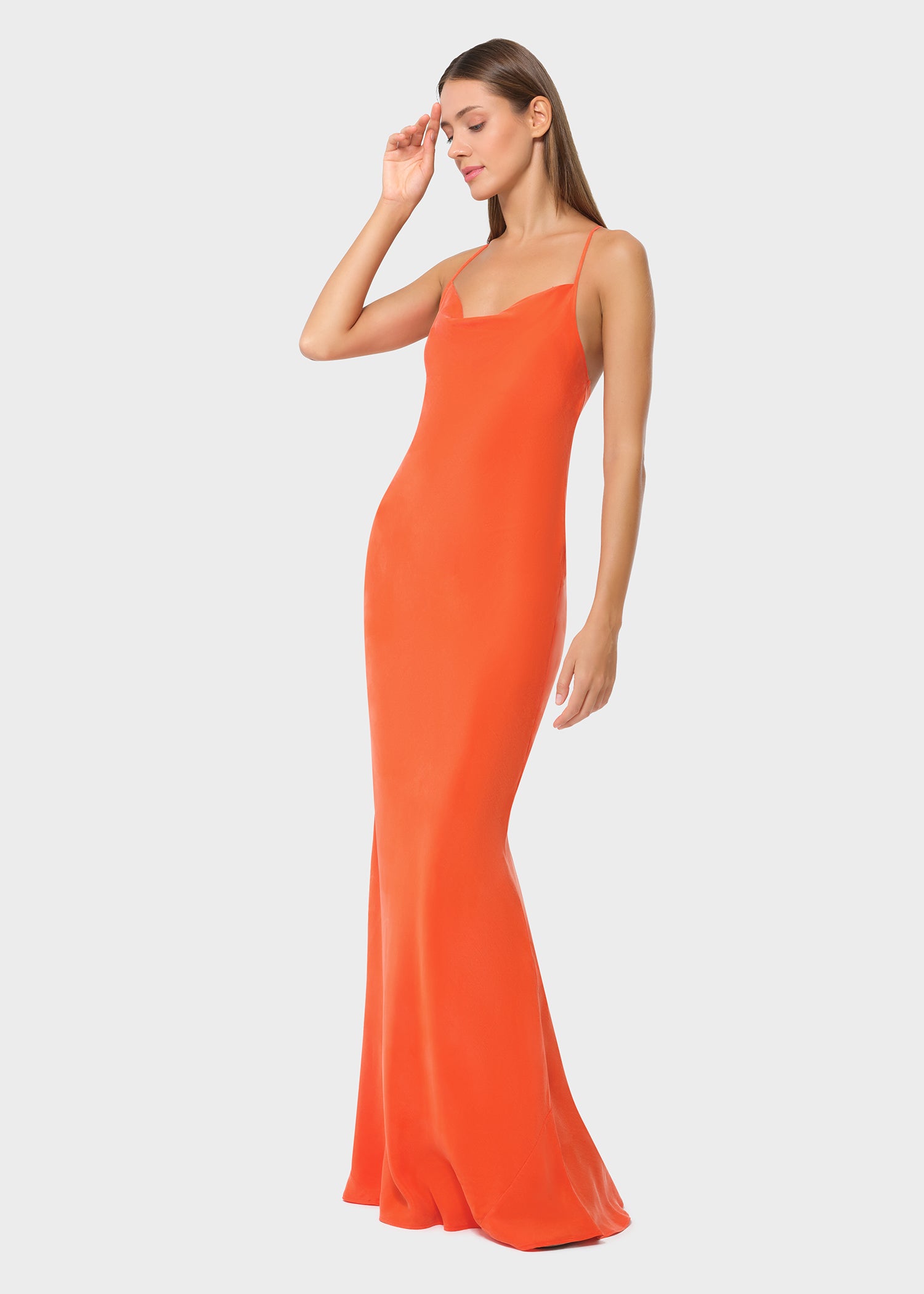 Woman wearing bright orange vegan silk slip maxi dress, side profile view