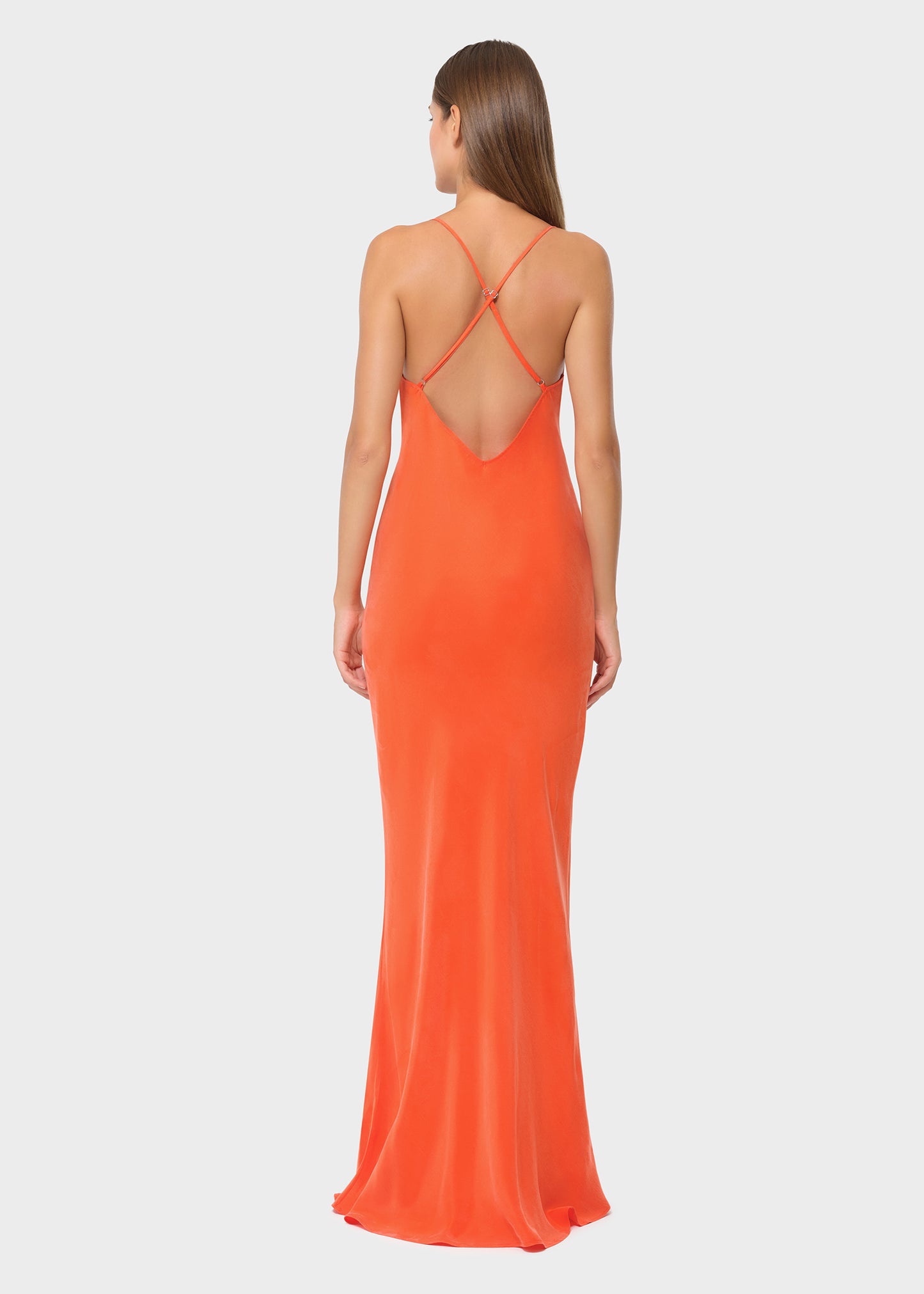 Woman wearing bright orange vegan silk slip maxi dress with crisscross open back, rear view