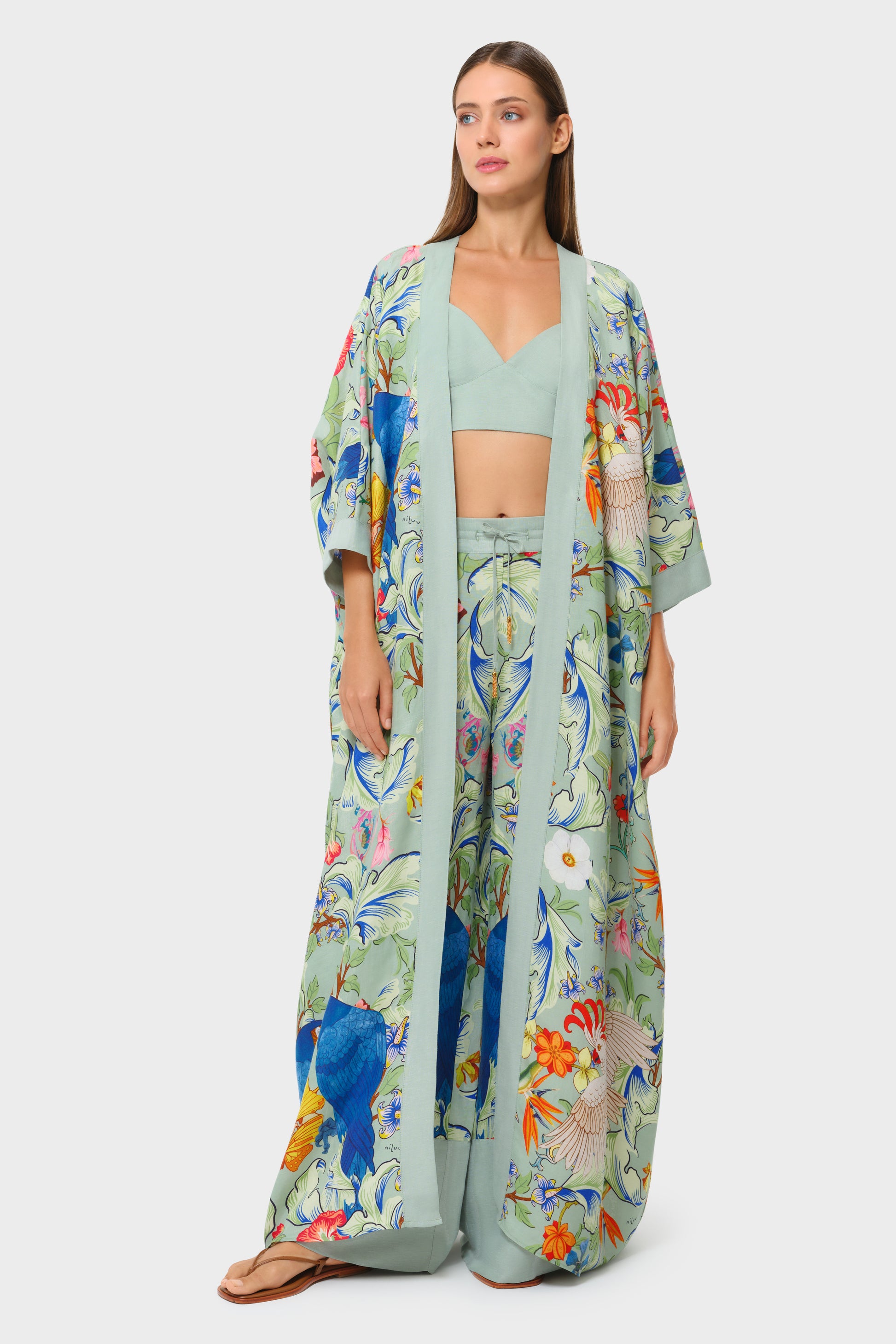 Model wearing a mint bralette, tropical print wide-leg pants, and matching open robe.
