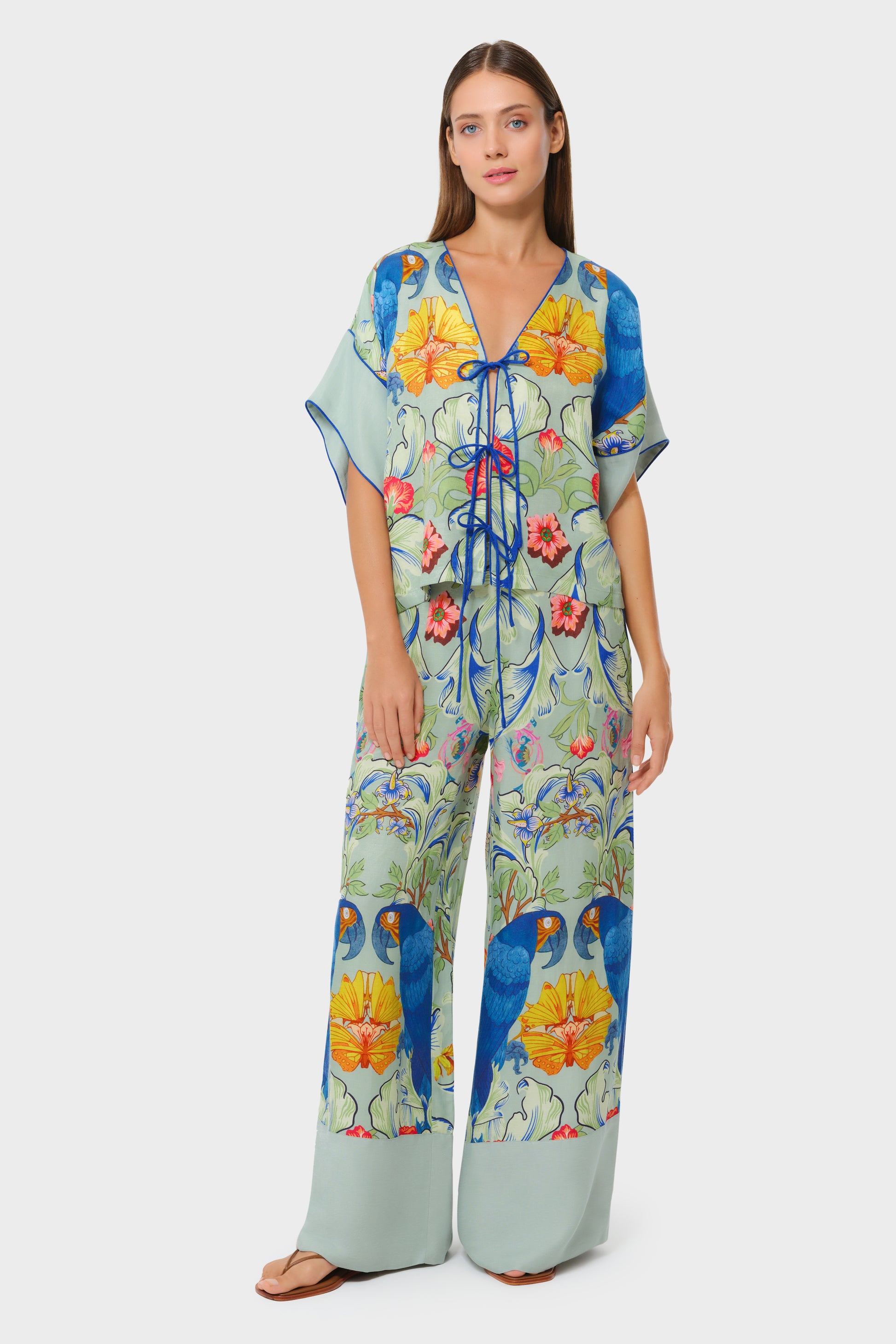 Model wearing printed sage green top with matching wide-leg pants on studio background