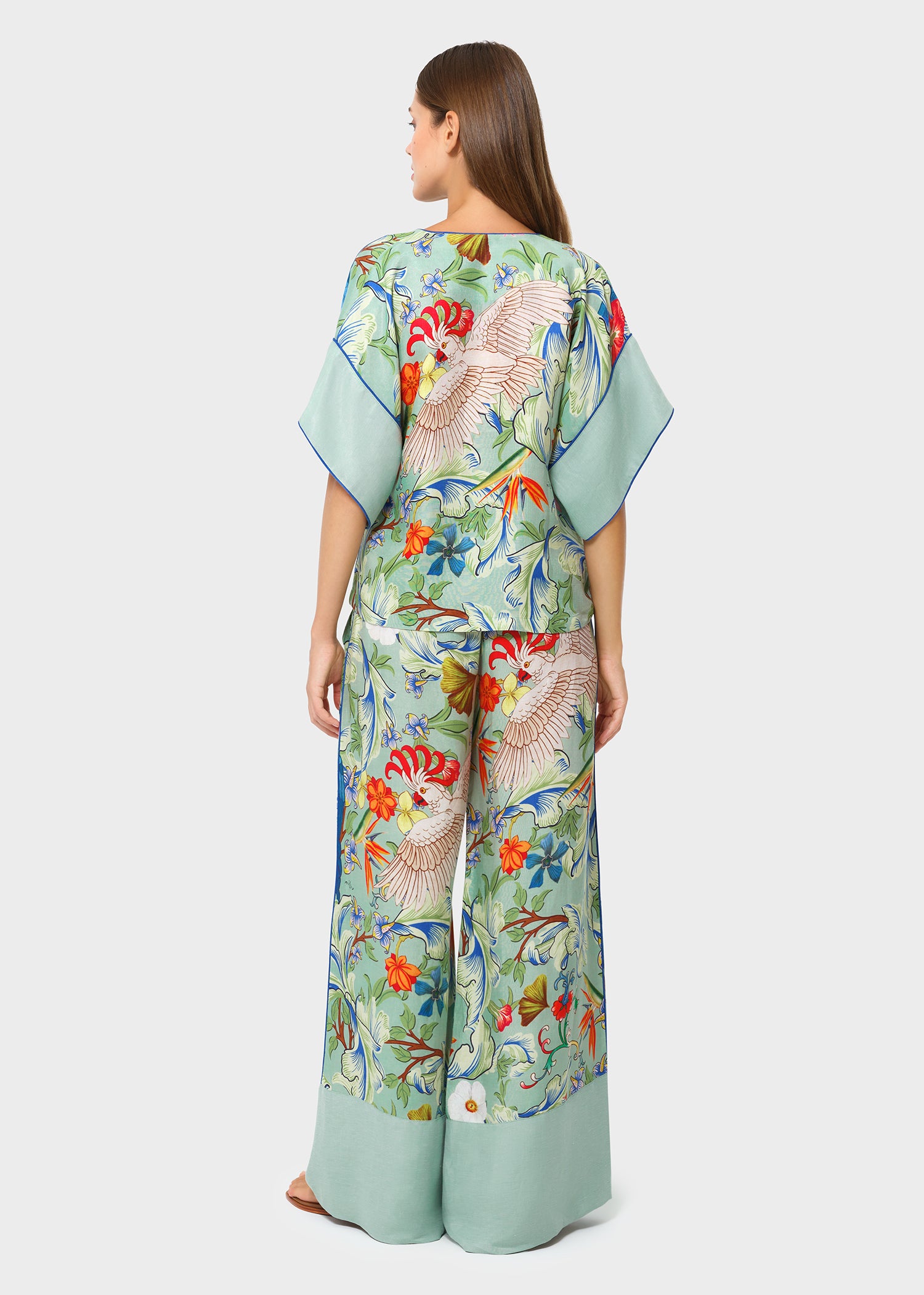 Back view of model wearing a tropical bird print co-ord set featuring a relaxed kimono-style top and wide-leg pants with soft green borders, styled against a clean studio background.