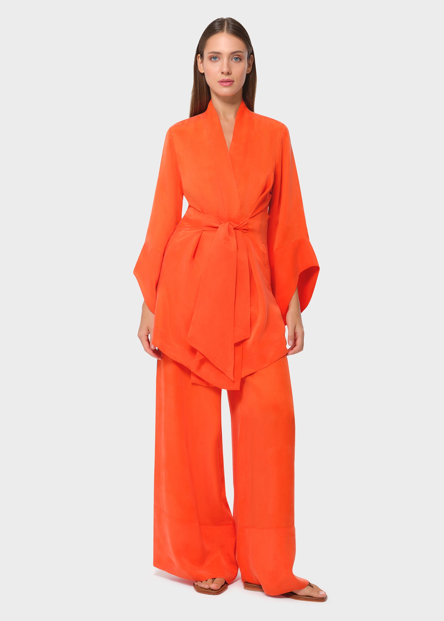 Model wearing a bright orange wrap lounge top with matching wide-leg pants, front view on studio background