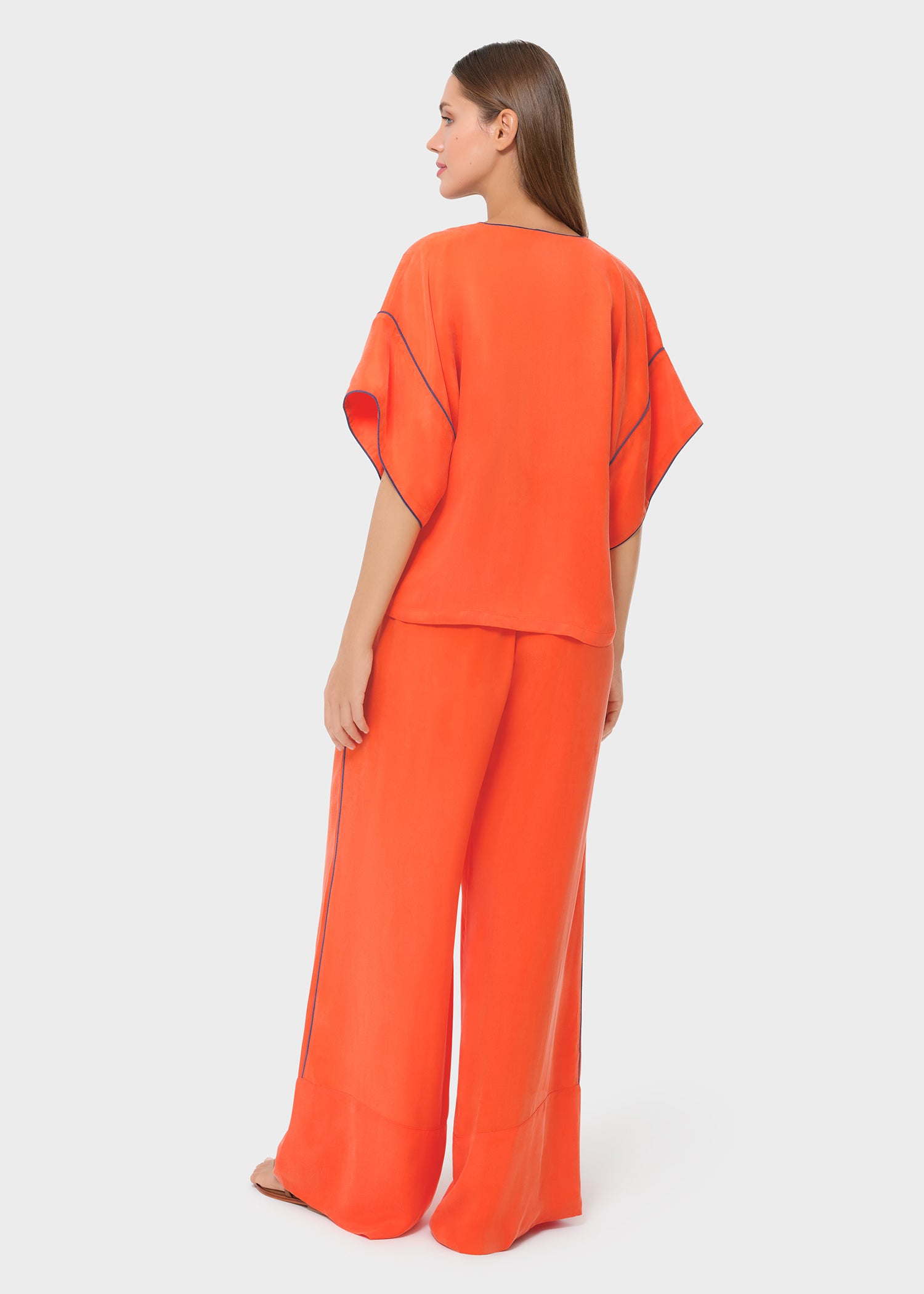 Back view of the bright orange co-ord set featuring a relaxed, flowy top with contrast piping and wide-leg pants for a breezy, effortless look.