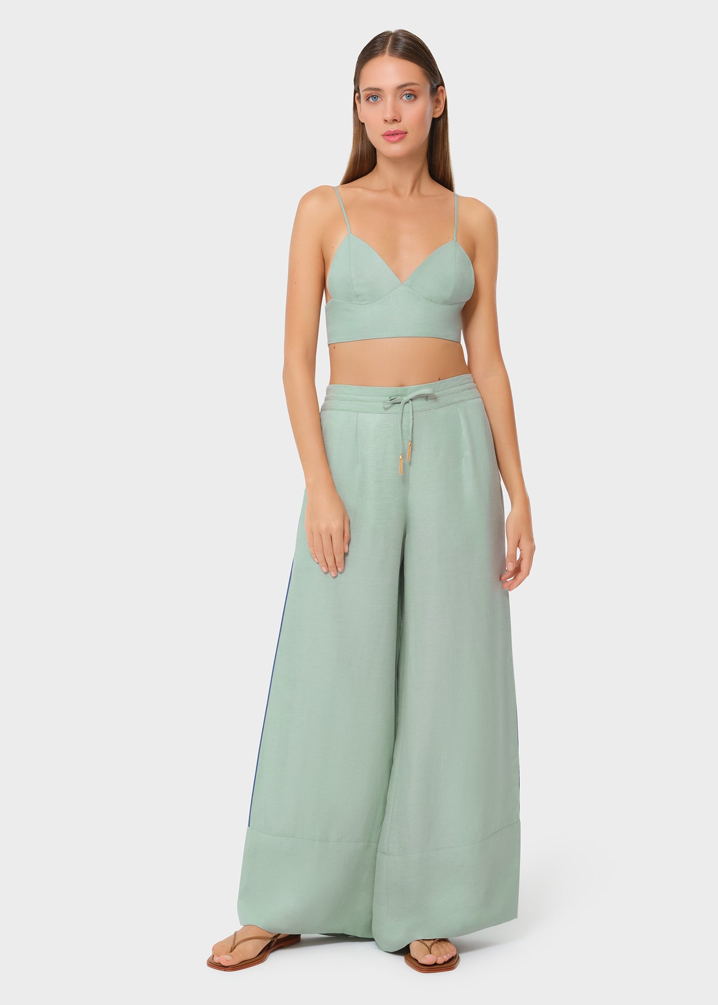 Model wearing a sage green bralette with matching drawstring wide-leg pants, front view on studio background