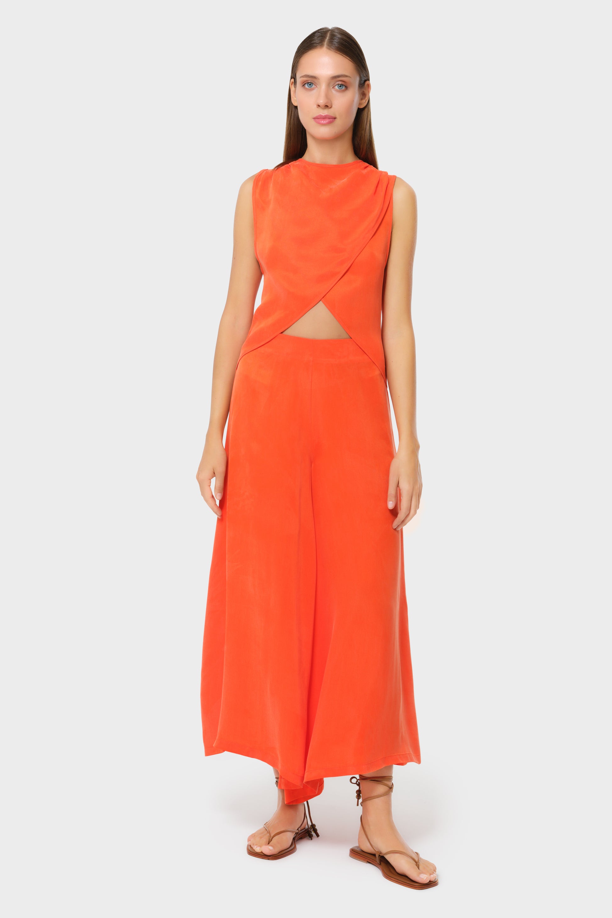 Model wearing a bright orange asymmetrical wrap top with matching high-waisted wide-leg pants, front view on studio background