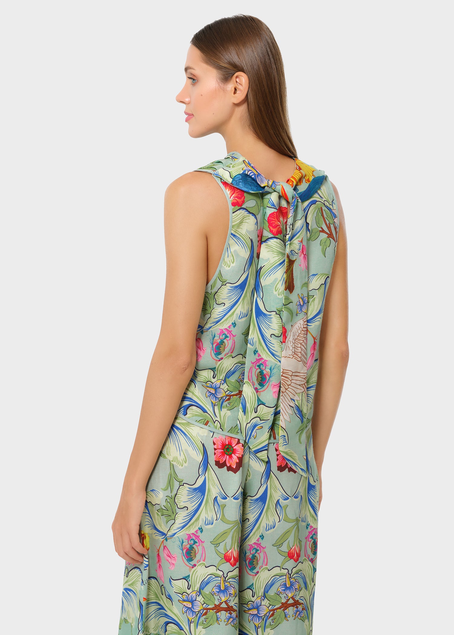Side back view of the tropical printed set featuring florals and parrots. Sleeveless top with a soft neck tie detail and relaxed, flowy silhouette.