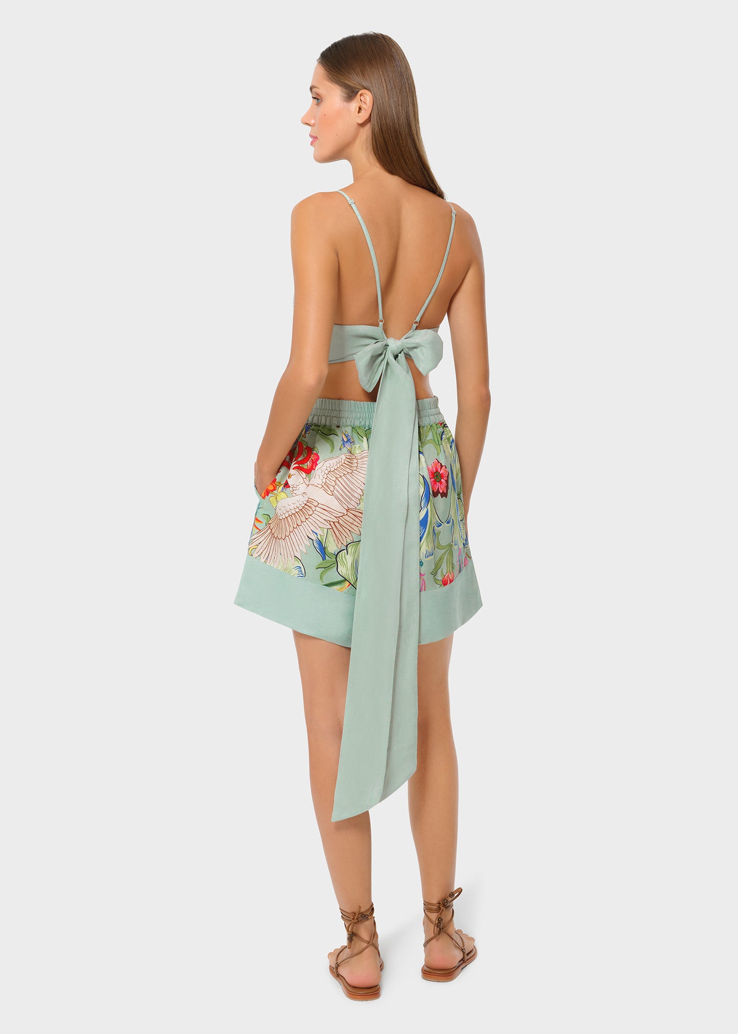 Back view of mint green bralette with tie bow detail paired with tropical print high-waisted shorts.