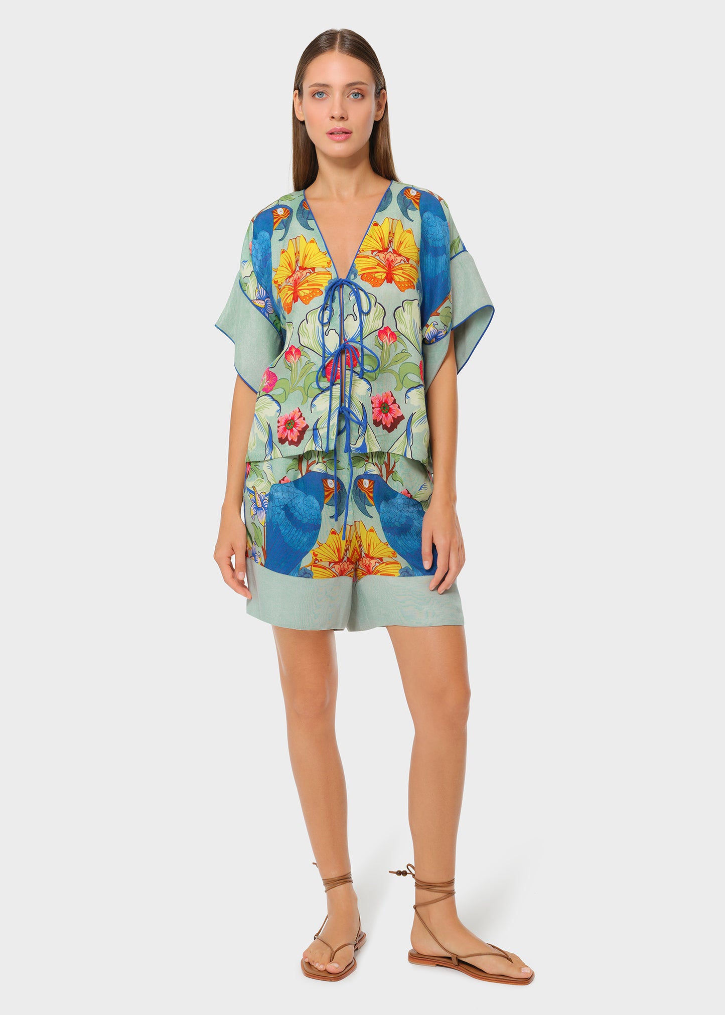 Model wearing a printed short set with a light green crop top and parrot-print shorts.