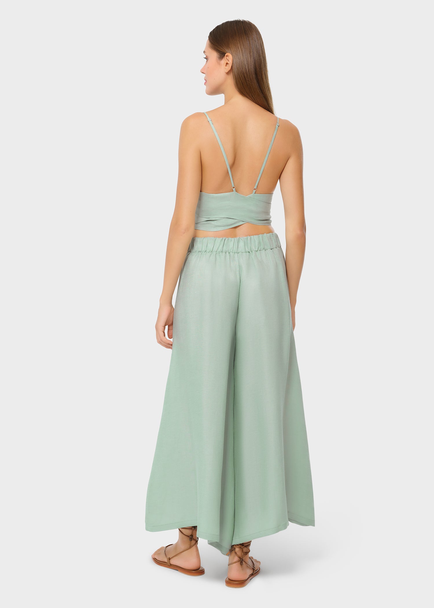 Woman wearing mint green vegan silk bralette and bow tie maxi skirt, back view