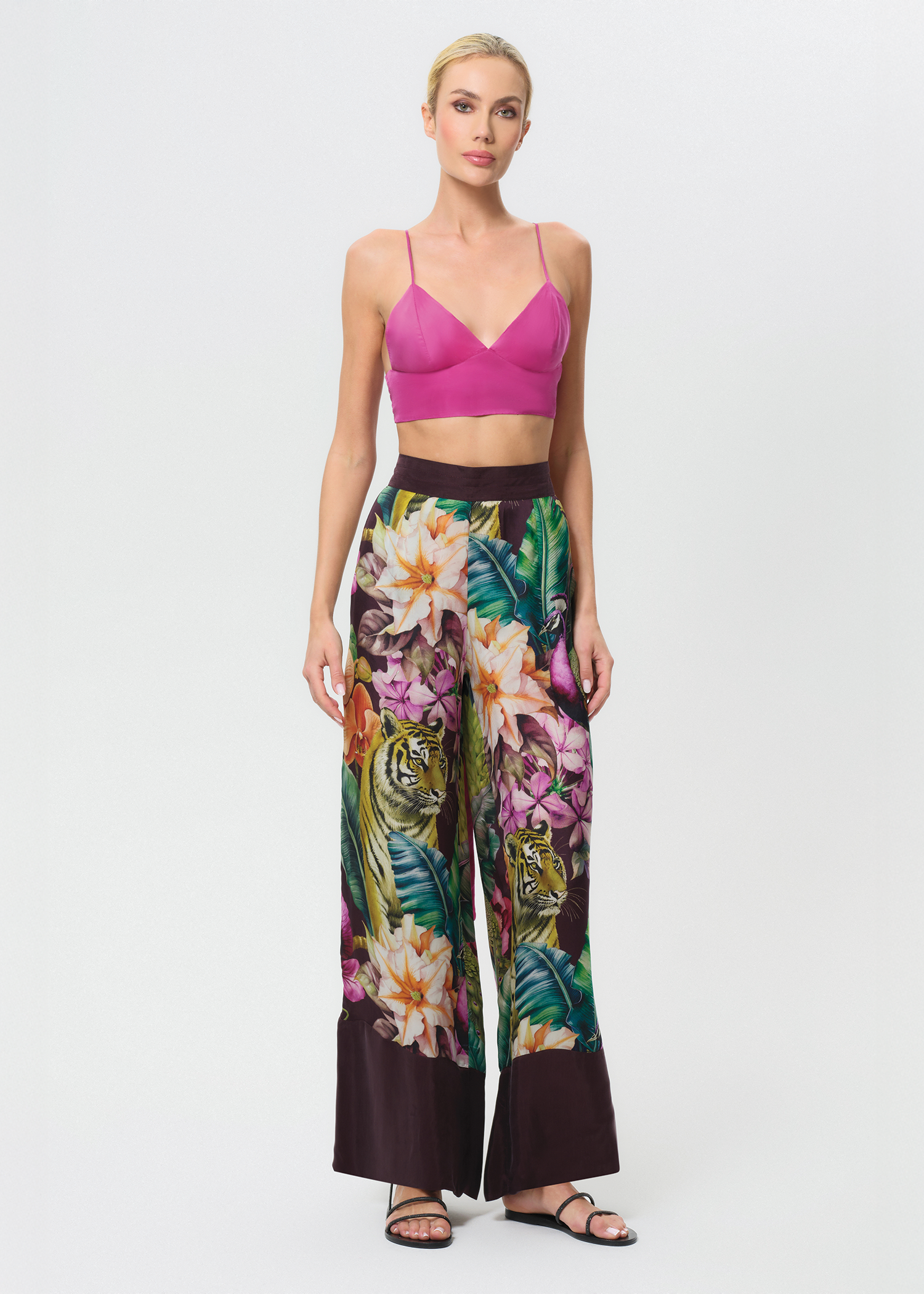 Woman wearing a pink top and colorful floral pants on a white background