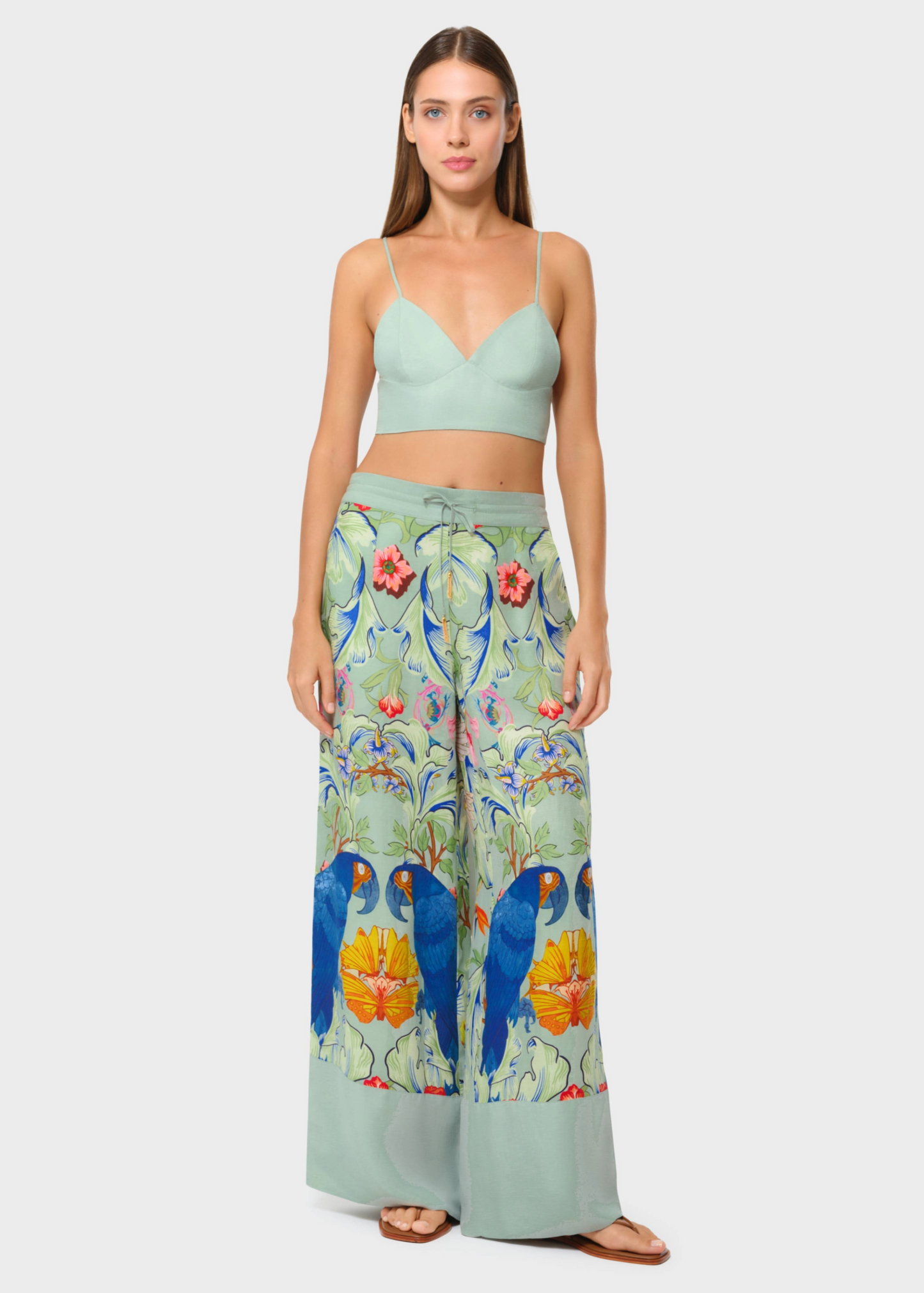 Model wearing a sage green bralette with printed wide-leg lounge pants, front view on studio background