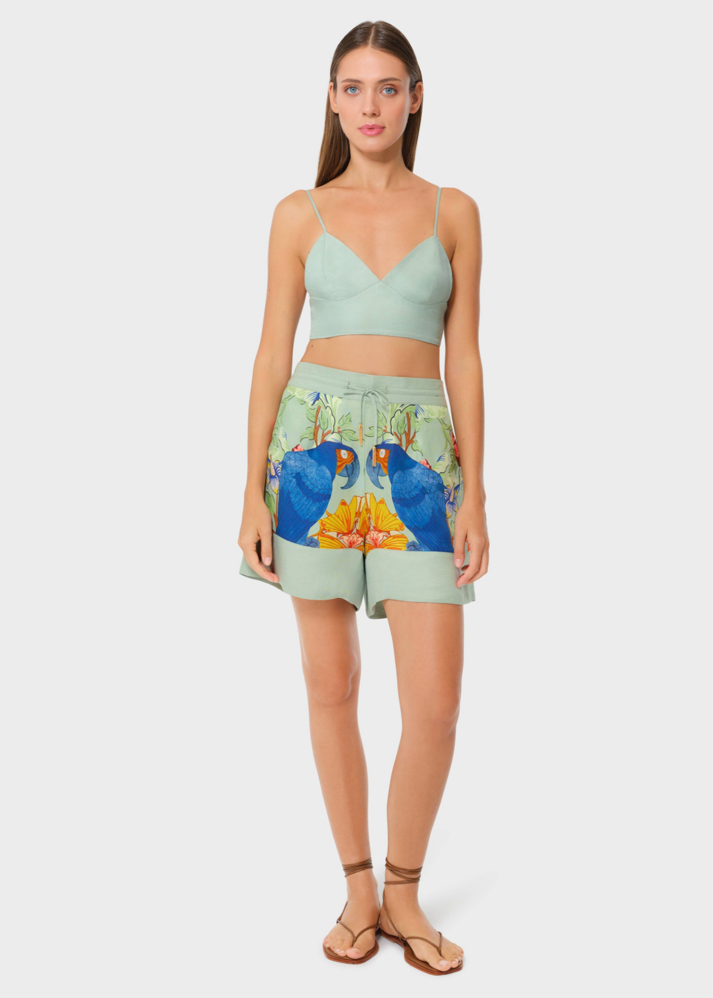 Model in sage green bralette with printed lounge shorts, studio background