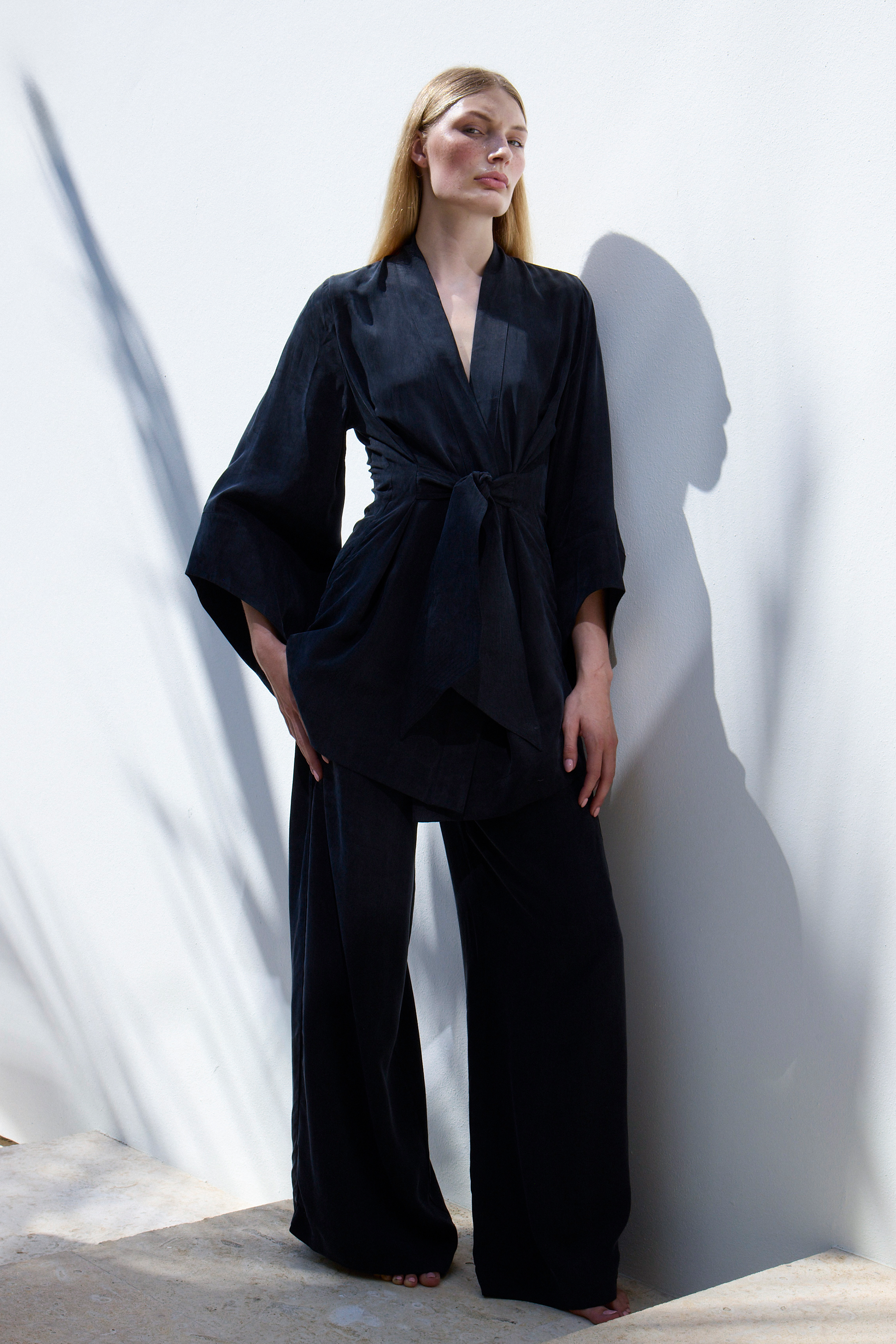 Model wearing Noir Amara Kimono Robe against white wall